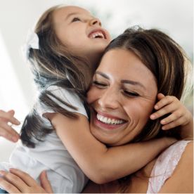 Laughing mother hugging her very young daughter